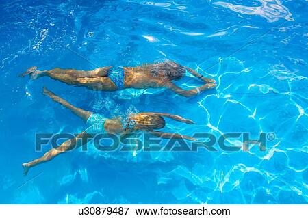Stock Photo - Girl and her mother swimming underwater in outdoor swimming pool, high angle view, Vernazza, Liguria, Italy. Fotosearch