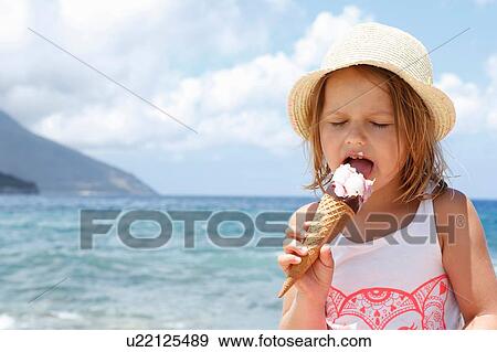 Stock Photo - Girl eating ice cream cone on beach, Scopello, Sicily, Italy. Fotosearch