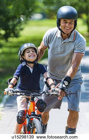 Stock Photo - Grandfather and grandson enjoying biking and roller skating. Fotosearch