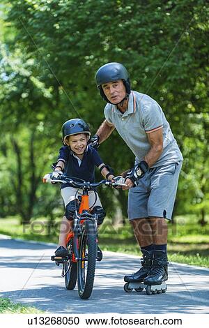 Grandfather teaching grandson how to ride a bike View Large Photo Image Stock Image - Grandfather teaching grandson how to ride a bike. Fotosearch