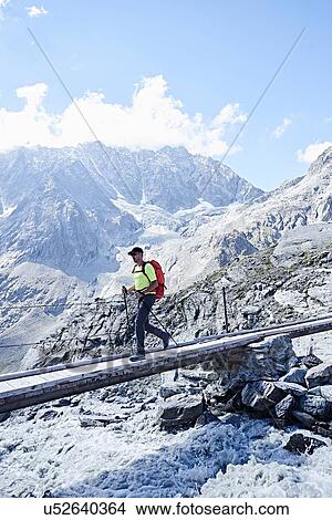 Picture - Hiker crossing narrow bridge, Mont Cervin, Matterhorn, Valais, Switzerland. Fotosearch
