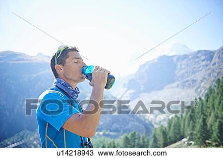 Stock Image - Hiker drinking from water bottle, Mont Cervin, Matterhorn, Valais, Switzerland. Fotosearch