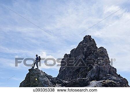Stock Photo - Hiker on peak of rock, Mont Cervin, Matterhorn, Valais, Switzerland. Fotosearch