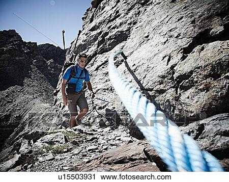 Stock Image - Hiker using rope to ascend rock face, Mont Cervin, Matterhorn, Valais, Switzerland. Fotosearch