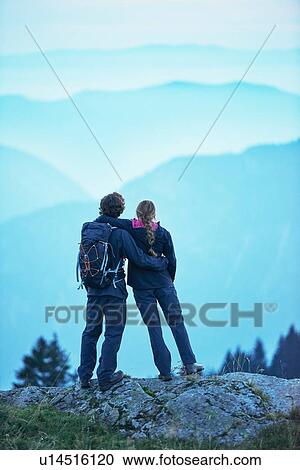 Stock Image - Hikers enjoying view of misty mountains, Manigod, Rhone-Alpes, France. Fotosearch