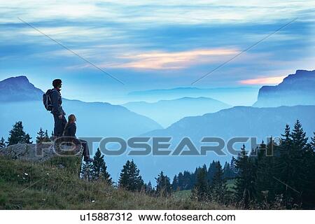 Stock Image - Hikers enjoying view of misty mountains, Manigod, Rhone-Alpes, France. Fotosearch