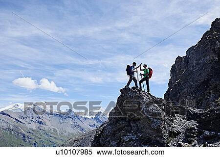 Stock Photography - Hikers high fiving on peak of rock, Mont Cervin, Matterhorn, Valais, Switzerland. Fotosearch