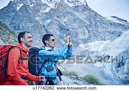 Stock Image - Hikers taking photograph, Mont Cervin, Matterhorn, Valais, Switzerland. Fotosearch