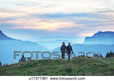 Stock Image - Hikers with misty mountains in background, Manigod, Rhone-Alpes, France. Fotosearch