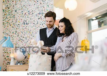 Stock Photo - Husband and pregnant wife shopping for soft toys. Fotosearch