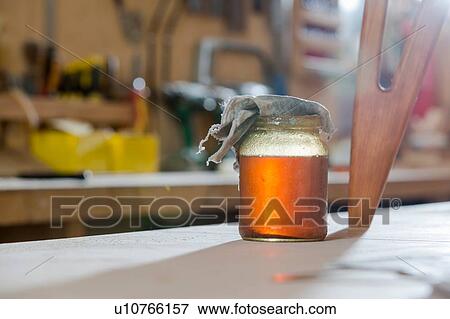 Stock Photo - Jar of oil finish beside wooden stool. Fotosearch