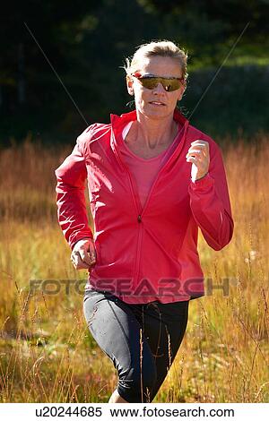 Stock Photography - Jogger running on grassy field. Fotosearch