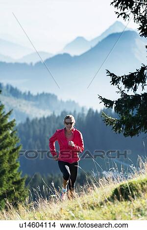 Picture - Jogger running up hillside, Manigod, Rhone-Alpes, France. Fotosearch