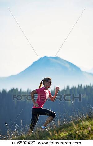 Stock Image - Jogger running up hillside, Manigod, Rhone-Alpes, France. Fotosearch