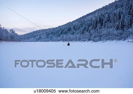Stock Photography - Landscape with distant view of man fishing on snow covered frozen lake. Fotosearch