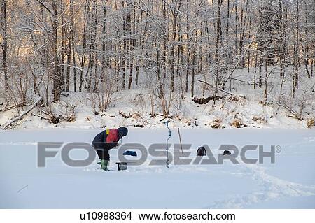 Picture - Landscape with man fishing on snow covered frozen lake. Fotosearch