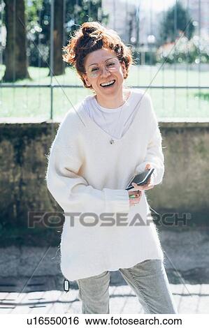 Stock Photograph - Laughing woman, cellphone in hand, Milan, Italy. Fotosearch