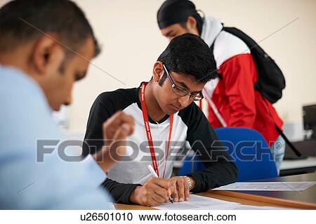 Stock Image - Lecturer talking to college students in classroom. Fotosearch