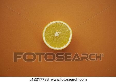 Stock Image - Lemon half on orange background. Fotosearch