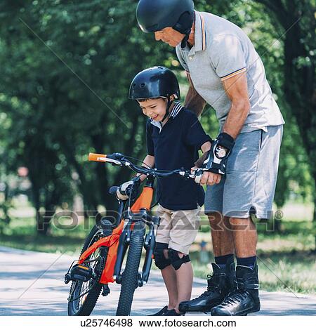 Stock Photo - Little boy with bicycle, getting help from his grandpa. Fotosearch