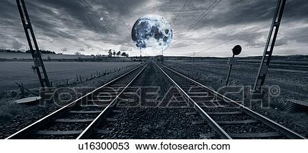 Stock Image - Long train track stretching towards the horizon and a jagged moon.. Fotosearch