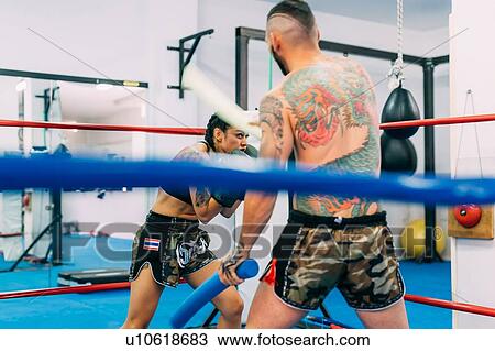 Stock Image - Male and female boxers working out in boxing ring. Fotosearch