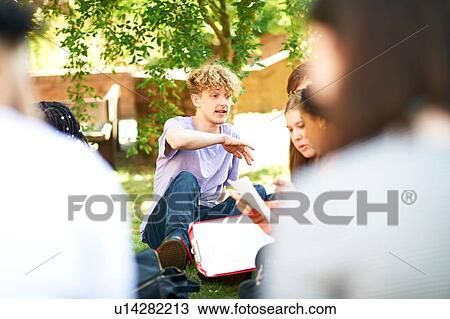 Male and female higher education students discussing paperwork on college campus lawn, over shoulder view View Large Photo Image Stock Image - Male and female higher education students discussing paperwork on college campus lawn, over shoulder view. Fotosearch