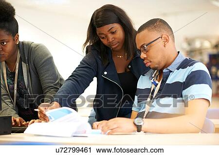 Stock Image - Male and female higher education students looking at paperwork in college classroom. Fotosearch