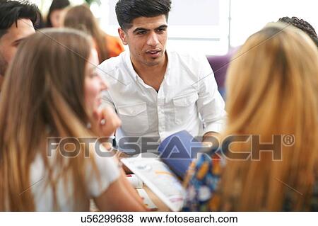 Stock Photo - Male and female higher education students discussing project in college classroom. Fotosearch