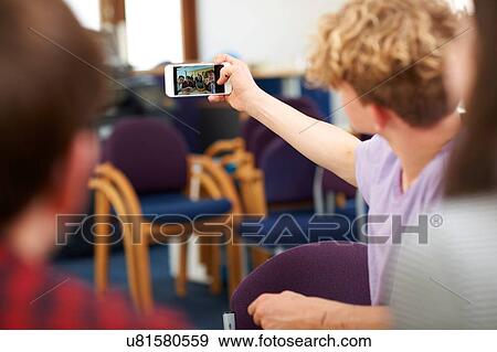 Stock Photo - Male and female higher education students taking selfie in college classroom. Fotosearch