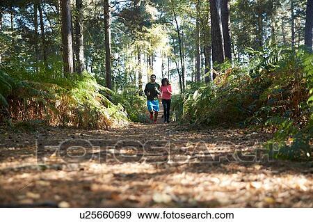 Stock Photo - Male and female runners running in forest. Fotosearch