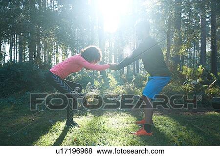 Male and female runners stretching legs and warming up in sunlit forest View Large Photo Image Stock Photo - Male and female runners stretching legs and warming up in sunlit forest. Fotosearch