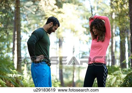 Stock Photo - Male and female runners taking a break in forest. Fotosearch