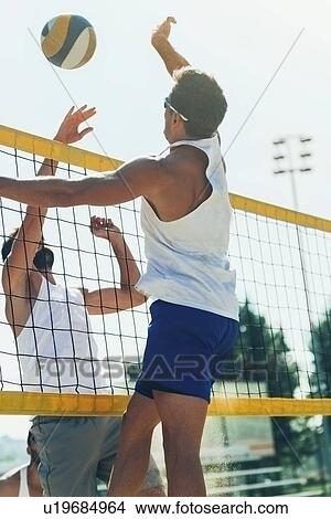 Male beach volleyball players jumping to hit the ball View Large Photo Image Picture - Male beach volleyball players jumping to hit the ball. Fotosearch