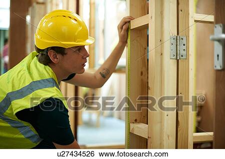 Stock Photograph - Male higher education student checking wooden framework in college workshop. Fotosearch