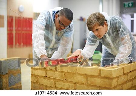 Picture - Male higher education students building brick wall in college workshop. Fotosearch