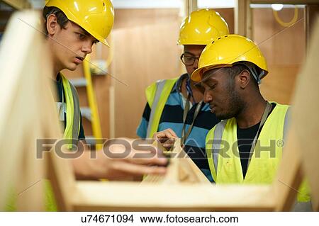 Picture - Male higher education students building wooden framework in college workshop. Fotosearch