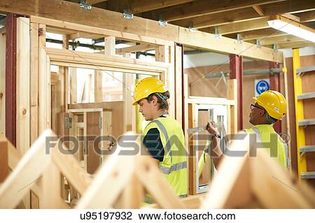Stock Image - Male higher education students building wooden framework in college workshop. Fotosearch