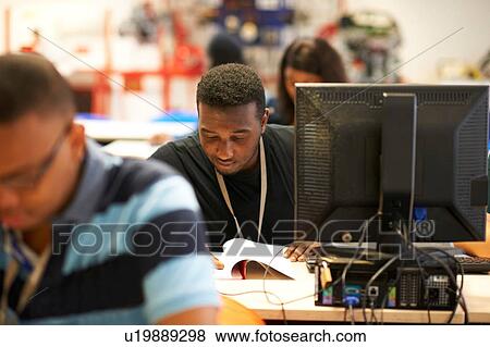 Stock Photo - Male higher education students working at desks in college classroom. Fotosearch