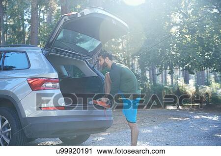 Male runner tying laces on car boot in sunlit forest View Large Photo Image Stock Image - Male runner tying laces on car boot in sunlit forest. Fotosearch