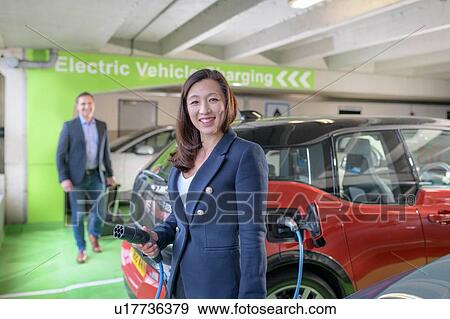 Man and woman charging electric car at charge bay, Manchester, UK View Large Photo Image Stock Photo - Man and woman charging electric car at charge bay, Manchester, UK. Fotosearch