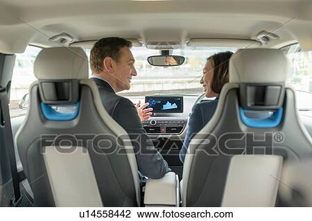 Stock Image - Man and woman sitting in electric car, Manchester, UK. Fotosearch