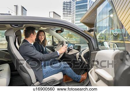 Man and woman sitting in electric car, Manchester, UK View Large Photo Image Stock Image - Man and woman sitting in electric car, Manchester, UK. Fotosearch
