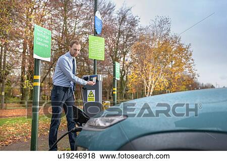 Man charging electric car at charge point, Manchester, UK View Large Photo Image Stock Photo - Man charging electric car at charge point, Manchester, UK. Fotosearch