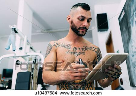 Picture - Man checking notepad in gym. Fotosearch