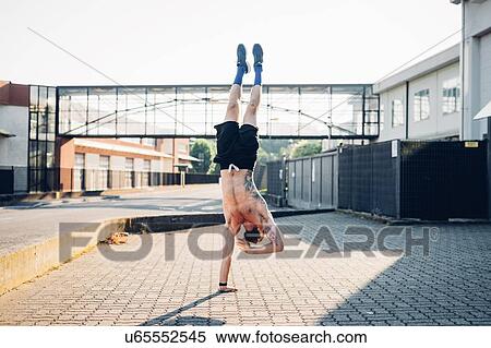 Stock Photography - Man doing single hand stand in sunshine. Fotosearch