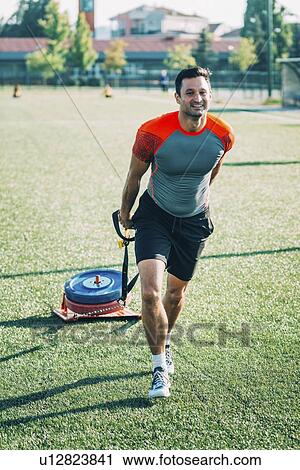 Stock Image - Man dragging a tyre. Fotosearch