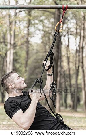 Man exercising with hanging fitness straps View Large Photo Image Stock Photo - Man exercising with hanging fitness straps. Fotosearch