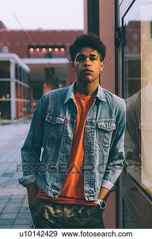 Stock Photo - Man leaning against glass window, Milan, Italy. Fotosearch