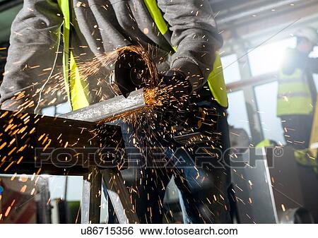 Stock Photograph - Man sawing metal panel. Fotosearch